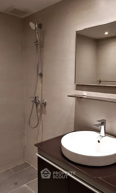 Modern bathroom with sleek fixtures and elegant design, featuring a stylish sink and shower area.