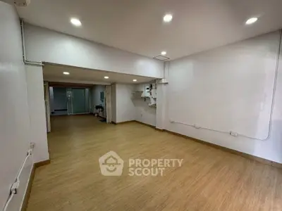 Spacious open-plan interior with wooden flooring and recessed lighting, ideal for versatile living or office space.
