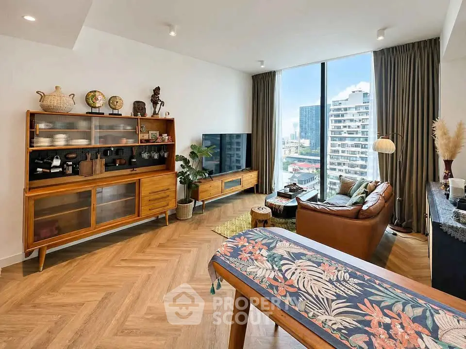 Stylish living room with modern decor and city view, featuring wooden furniture and large window.