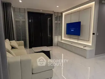 Modern living room with sleek design, featuring a wall-mounted TV and elegant lighting.