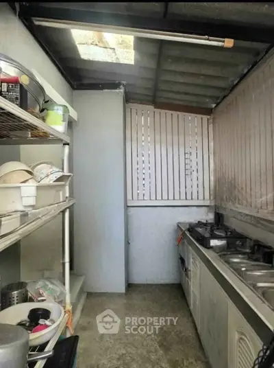 Compact kitchen with open layout and gas stove, featuring practical shelving and natural light.