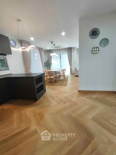 Spacious open-plan dining area with modern lighting and wooden flooring.