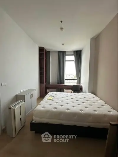 Spacious bedroom with large window and modern furnishings in a stylish apartment.