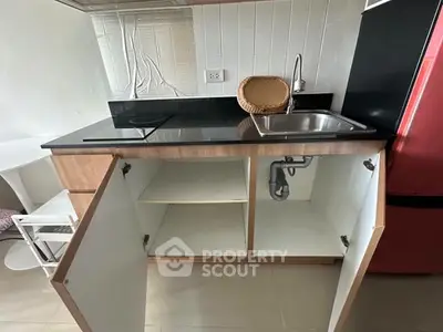 Compact kitchen with open cabinets, sleek countertop, and modern sink in a cozy apartment.