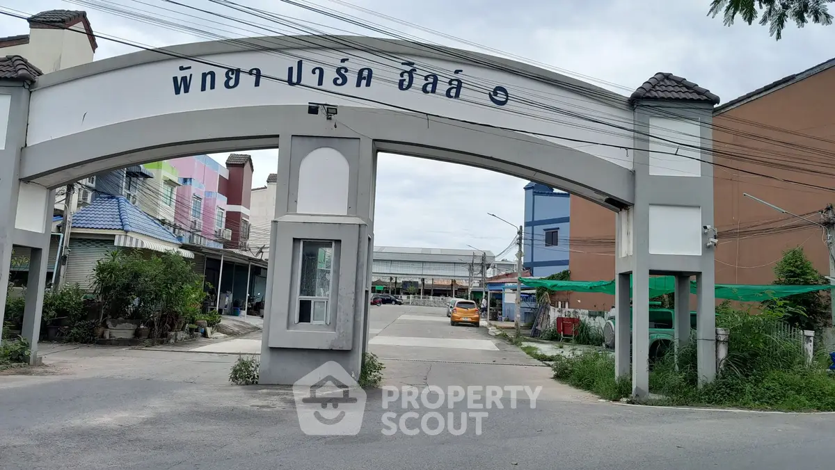 Charming residential entrance with archway and vibrant surroundings in a peaceful neighborhood.