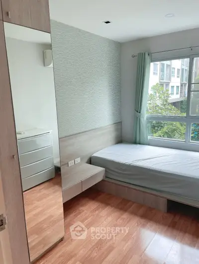 Modern bedroom with large window and wooden flooring in a cozy apartment