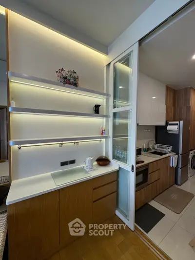 Modern kitchen with sleek cabinetry and built-in appliances, featuring open shelving and elegant lighting.