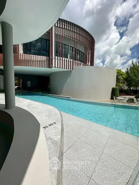Luxurious modern building with sleek poolside view and contemporary architecture.