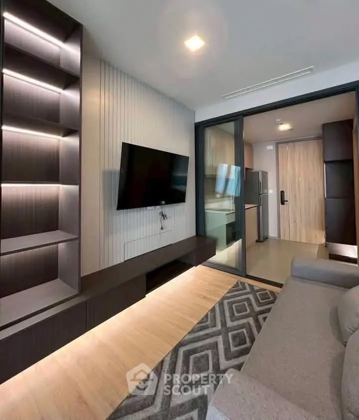 Modern living room with sleek design, built-in shelves, and open kitchen layout in a stylish apartment.