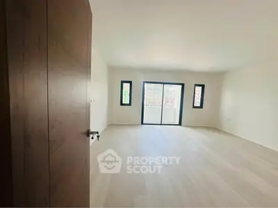 Spacious empty room with large windows and wooden flooring, perfect for customization.