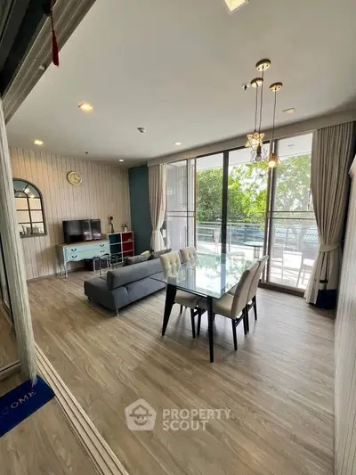 Spacious living room with modern decor and large windows opening to a balcony.