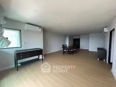 Spacious modern living room with wooden flooring and minimalist furniture.