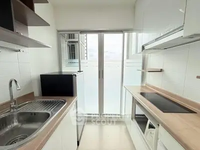 Modern kitchen with sleek white cabinets and built-in appliances, featuring a compact design.