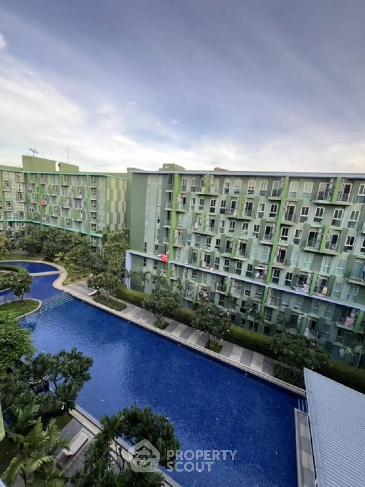 Modern apartment complex with large swimming pool and lush greenery