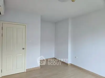 Spacious empty room with wooden flooring and white walls, ready for customization.