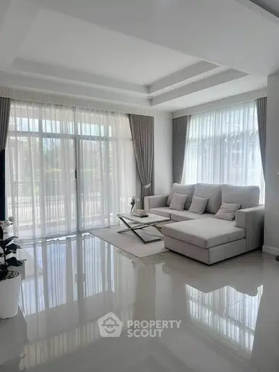 Elegant living room with large windows and modern furniture, offering a bright and airy atmosphere.