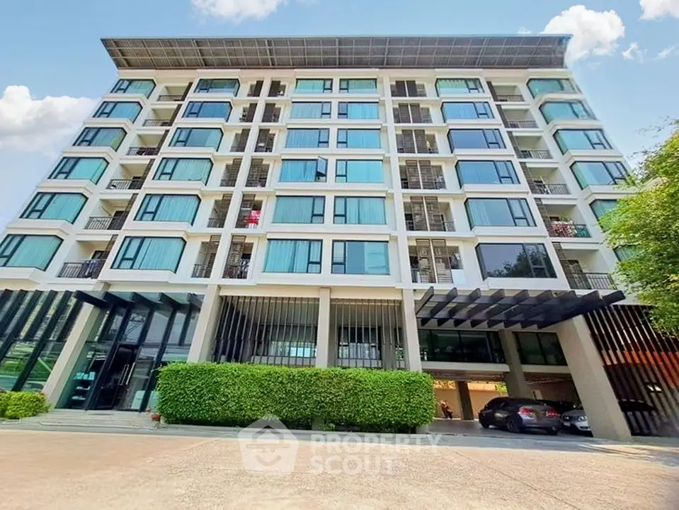 Modern apartment building with large windows and greenery, ideal urban living.
