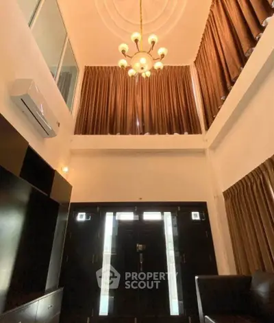 Stunning high-ceiling living room with elegant chandelier and large windows for natural light.