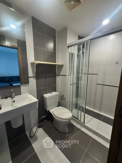 Modern bathroom with sleek design, featuring a glass shower enclosure and contemporary fixtures.