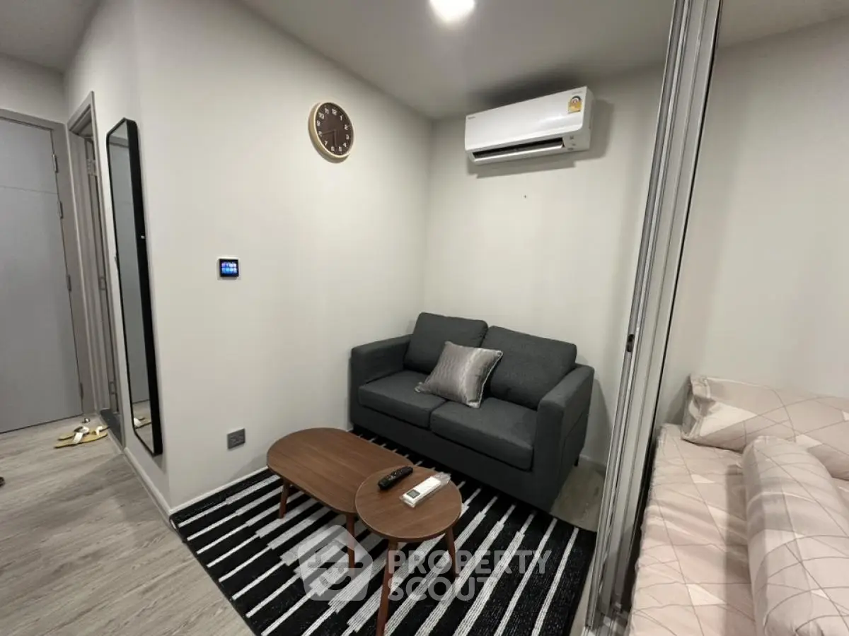 Cozy modern living room with sofa, wall clock, and air conditioning unit