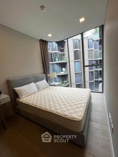 Modern bedroom with large windows and stylish decor in a luxury apartment.