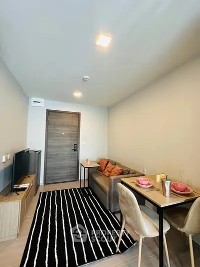Modern living room with cozy sofa, dining table, and stylish decor in a compact apartment.