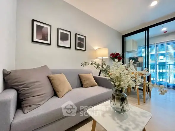 Modern living room with cozy sofa and stylish decor, open layout leading to a bright kitchen area.