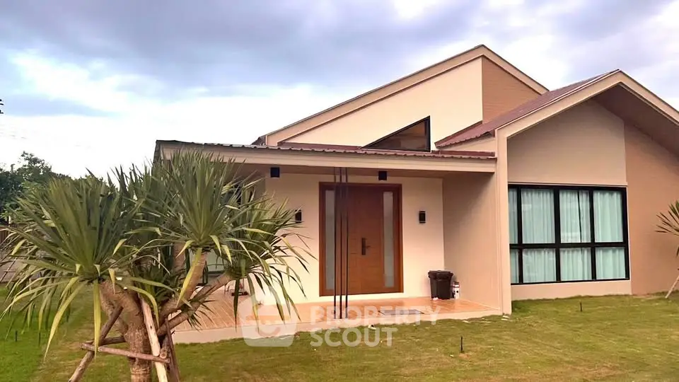 Modern single-story house with large windows and lush green lawn, perfect for family living.