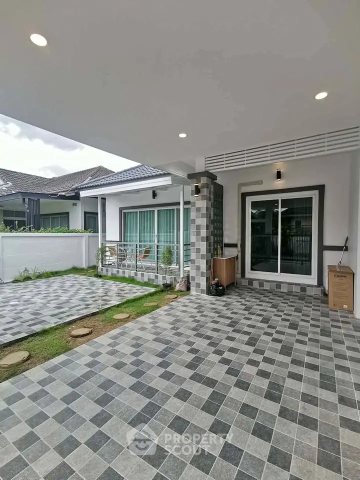 Modern home exterior with spacious tiled patio and large windows, perfect for outdoor gatherings.