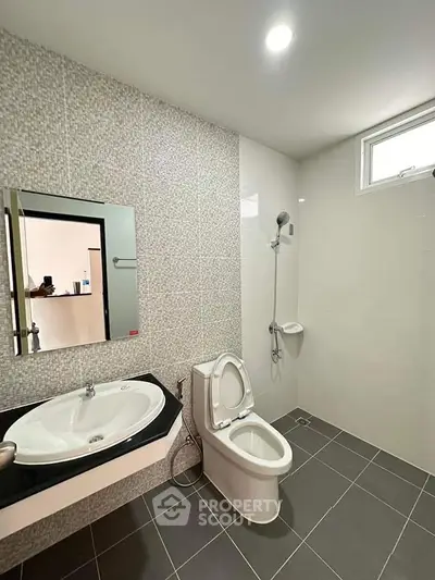 Modern bathroom with sleek fixtures and tiled walls, featuring a spacious shower and elegant sink.