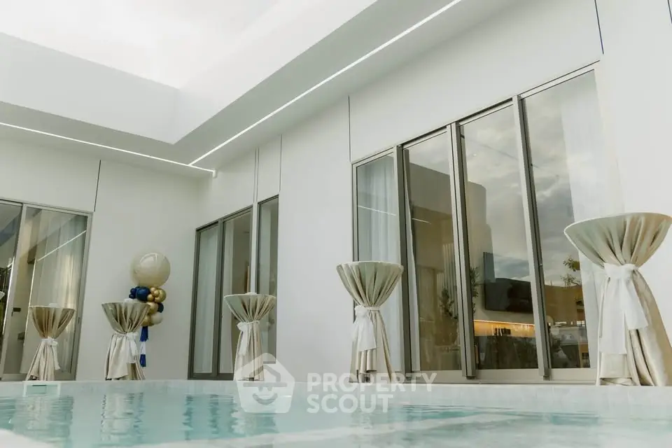 Luxurious modern poolside area with elegant decor and large windows, perfect for relaxation and entertainment.