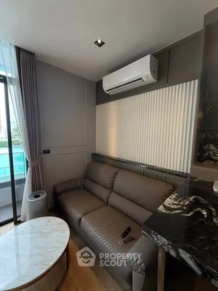 Modern living room with sleek sofa and air conditioning, featuring a marble coffee table and elegant decor.