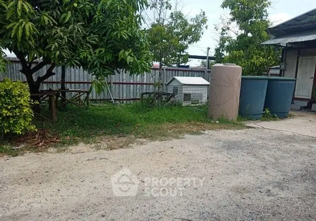 Charming backyard with greenery and storage tanks, perfect for outdoor activities.