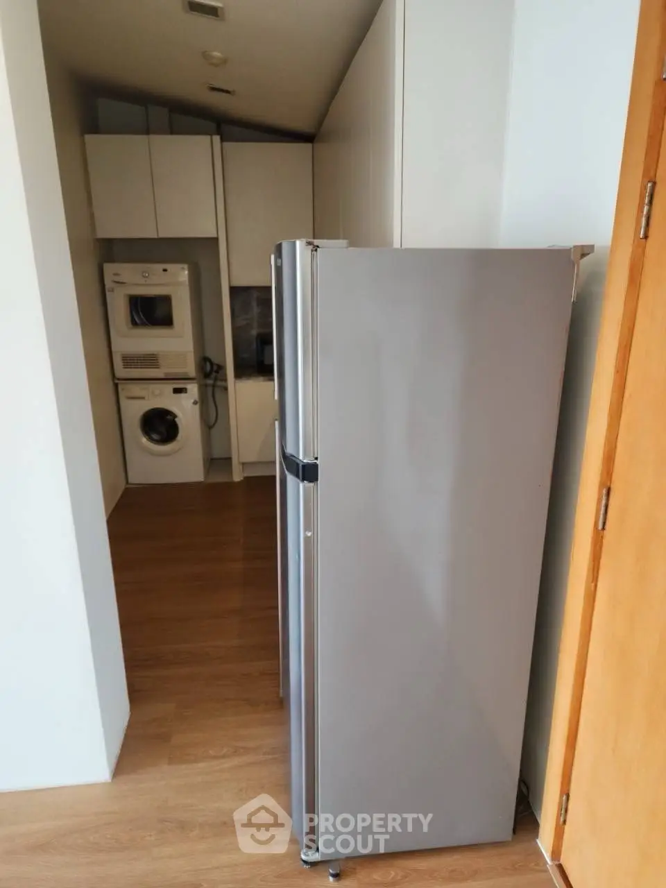 Modern kitchen with sleek appliances and in-unit laundry setup, featuring a spacious fridge and washer-dryer combo.