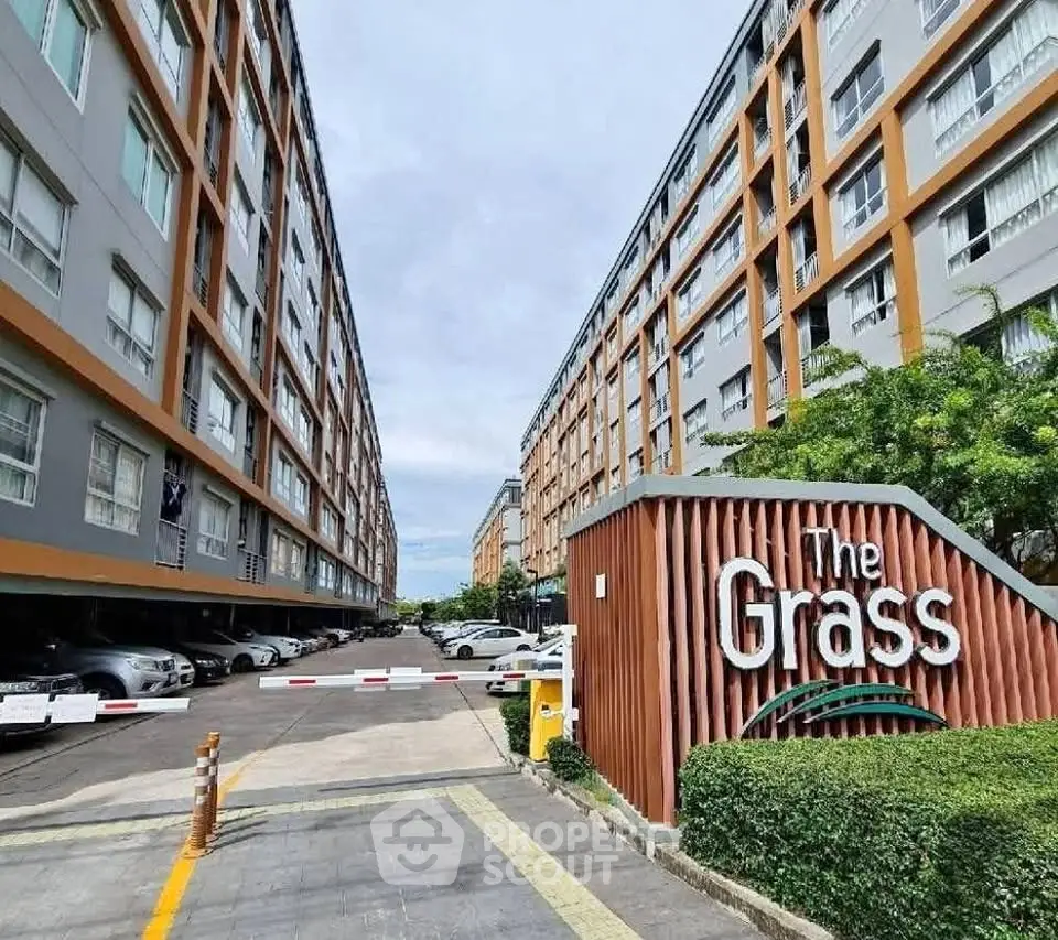 Modern condominium building with ample parking and stylish entrance signage.