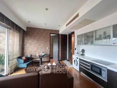 Modern living room with open kitchen, featuring washing machine and microwave, elegant decor and natural light.