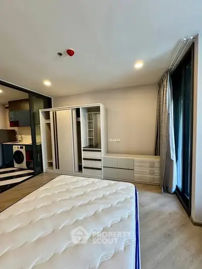 Modern bedroom with built-in wardrobe and large windows in a stylish apartment.