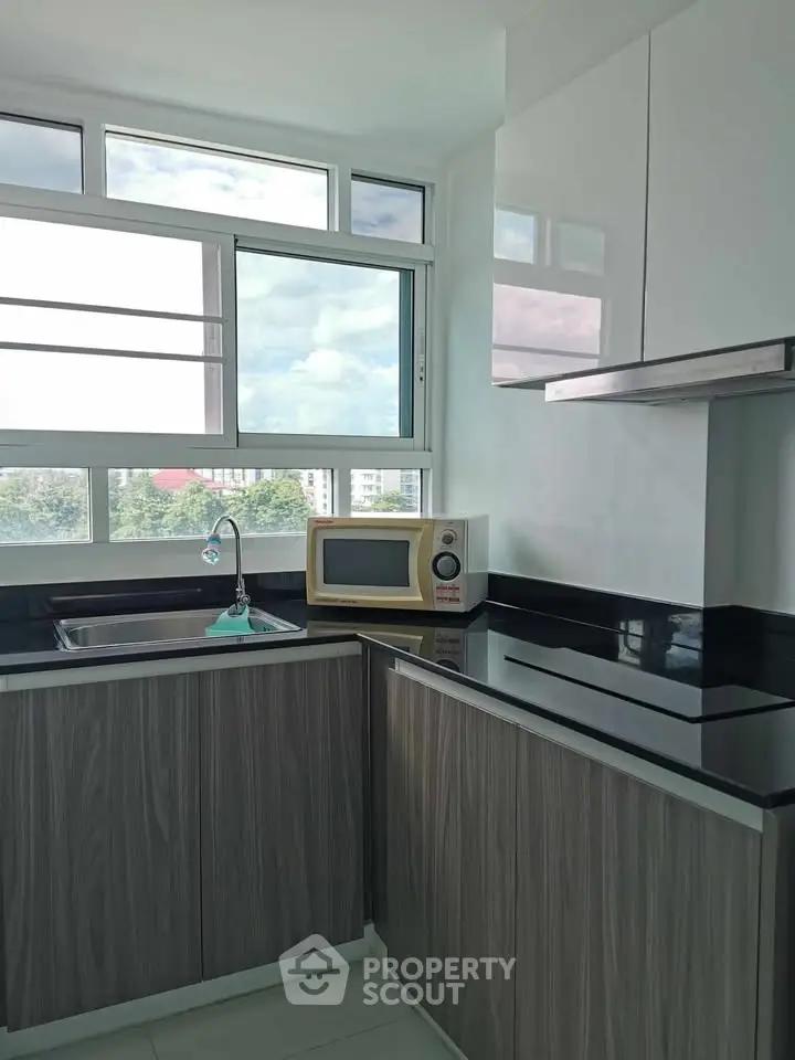 Modern kitchen with sleek cabinets and large window offering natural light and scenic views.