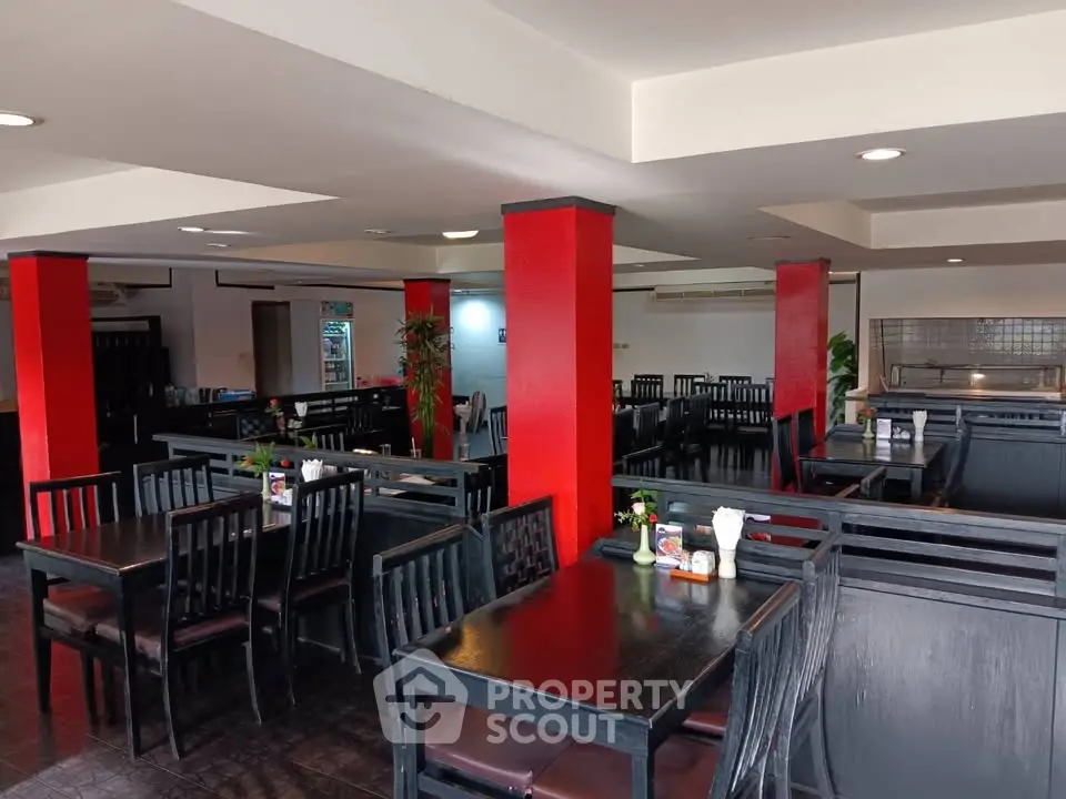 Spacious dining area with modern black furniture and vibrant red accents, perfect for gatherings.