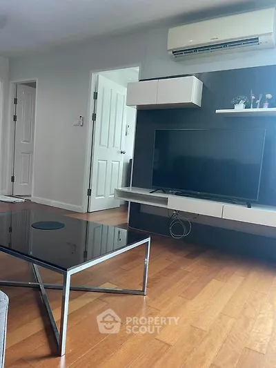 Modern living room with sleek TV unit and air conditioning, featuring stylish wooden flooring.