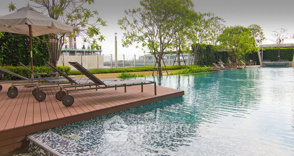 Luxurious outdoor pool area with sun loungers and lush greenery, perfect for relaxation and leisure.