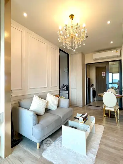 Elegant living room with chandelier and modern decor in a cozy apartment setting.