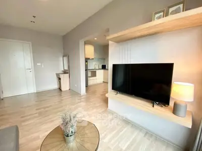 Modern living room with sleek TV setup and open kitchen layout in stylish apartment.
