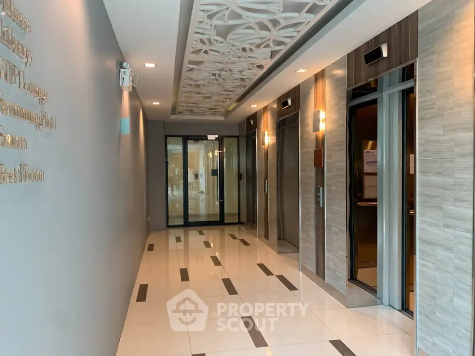Modern building lobby with stylish elevators and decorative ceiling design.