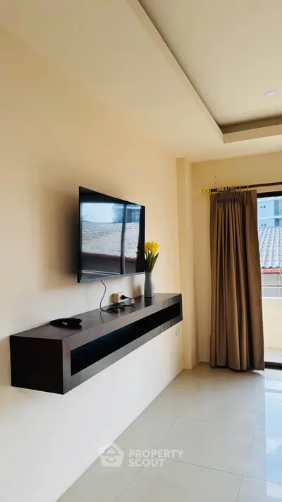 Modern living room with wall-mounted TV and sleek floating shelf, featuring a large window with curtains.