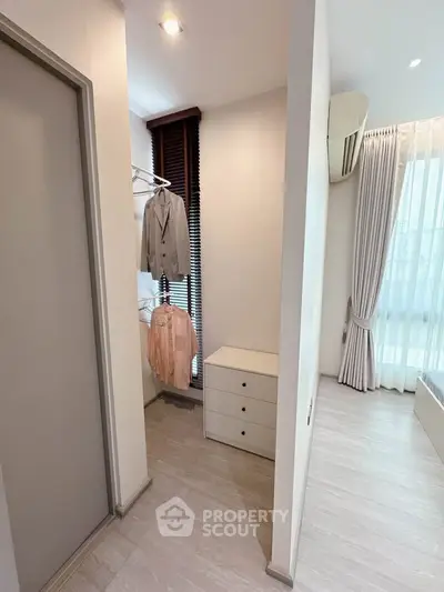 Modern bedroom with sleek design and ample natural light, featuring a small closet area and minimalist decor.
