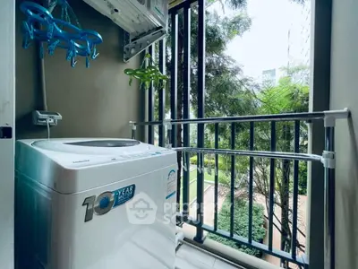Compact balcony with washing machine and lush garden view, ideal for urban living.