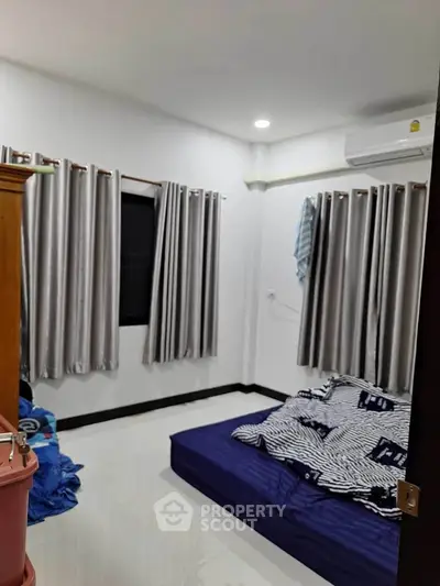 Cozy bedroom with minimalist decor and air conditioning, featuring a comfortable mattress and modern curtains.