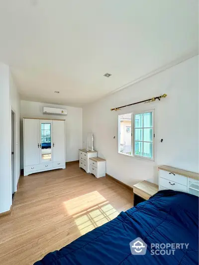 Spacious bedroom with wooden flooring and natural light in modern home