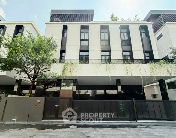 Modern multi-story building with sleek design and lush greenery in urban setting.